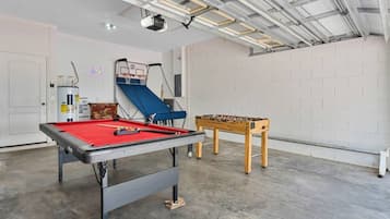 A recreational room with a pool table, a foosball table, and a ping pong table.