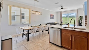 A modern kitchen with a dining area, large windows, and a view of the outdoors.