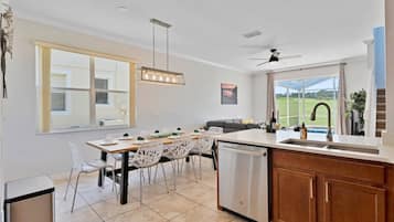 A modern kitchen with a dining area, large windows, and a view of the outdoors.