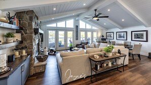 A spacious living area with a stone fireplace, a large window, and a ceiling fan.