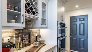 A modern kitchen with built-in appliances, a wine rack, and a corkboard with a motivational quote.