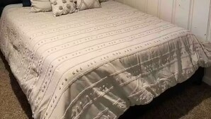A neatly made bed with a dark headboard, a patterned bedspread, and several pillows. - The Cozy Below (Edgewater)