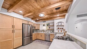Une cuisine moderne avec des meubles en bois, des appareils électroménagers en acier inoxydable et un plan de travail en marbre.