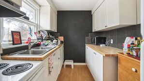 Kompakti keittiö, jossa on pesuallas, liesi, mikroaaltouuni ja puinen työtaso.