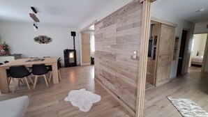 A modern living room with a wooden floor, a dining area with a table and chairs, a fireplace, and a large wooden partition. - House 3★ with Sauna & Games Room: The Ideal Family Hideaway (Bussang)