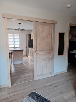 A modern kitchen with wooden cabinets, a stainless steel refrigerator, and a dining area with a glass bowl on the table.
