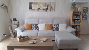 A modern living room with a sectional sofa, a wooden coffee table, and a bookshelf filled with board games. - House 3★ with Sauna & Games Room: The Ideal Family Hideaway (Bussang)