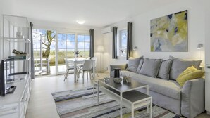 A modern living room with a sofa, coffee table, and dining area.