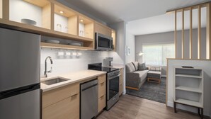 A modern kitchen with built-in appliances, a dining area with a sofa, and a view of the outdoors. - Towneplace Suites By Marriott Hickory (Hickory)