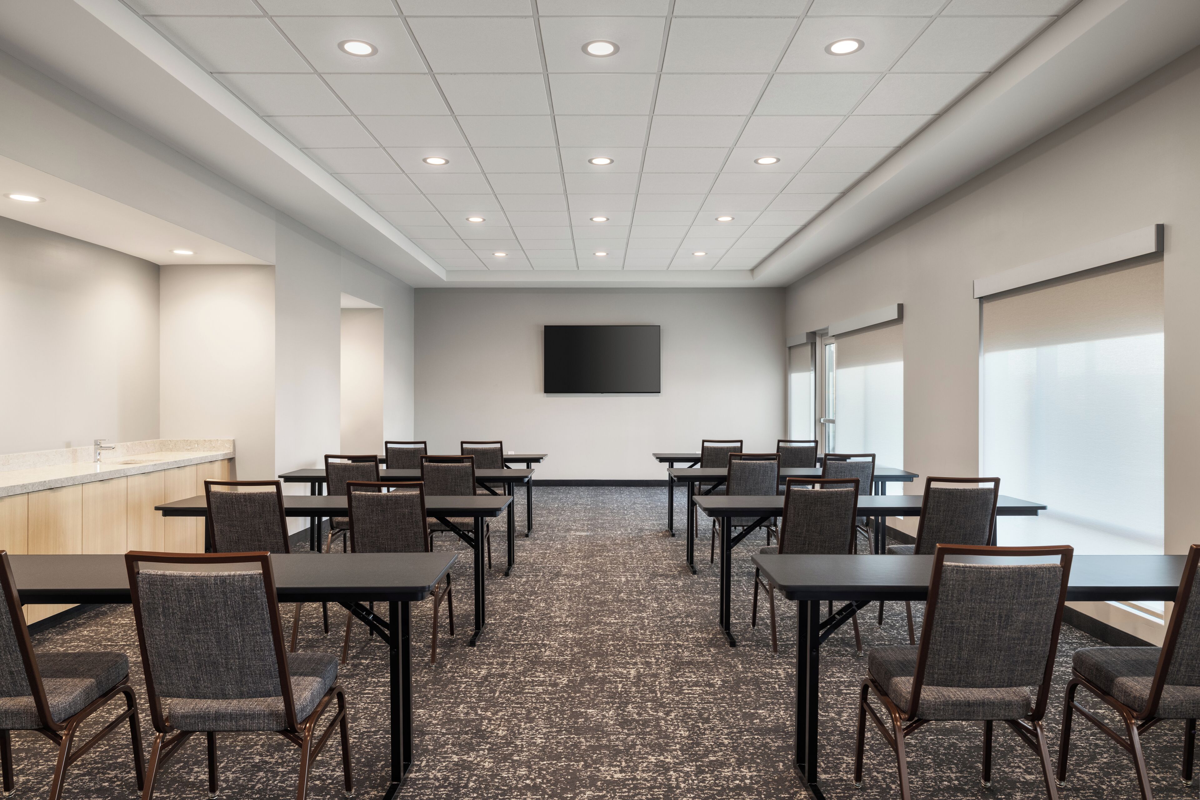 A conference room with a long table, chairs, a projector screen, and a large window.