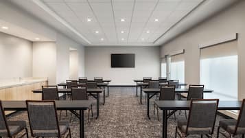 A conference room with a long table, chairs, a projector screen, and a large window.