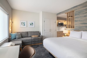 A hotel room with a bed, a sofa, a small table, a chair, a desk, a microwave, a lamp, and artwork on the walls. - Towneplace Suites By Marriott Hickory (Hickory)