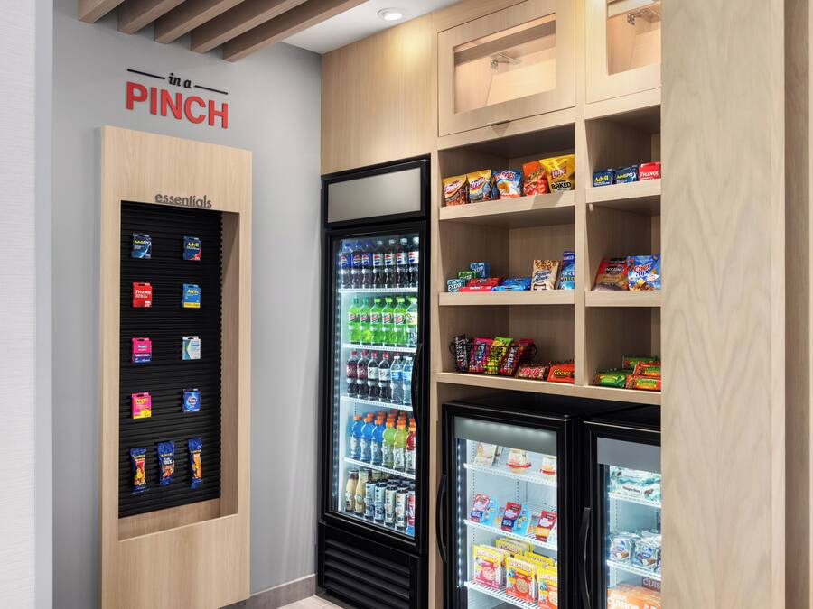 A vending machine with snacks and drinks, a refrigerator with beverages, and a shelf with packaged goods.
