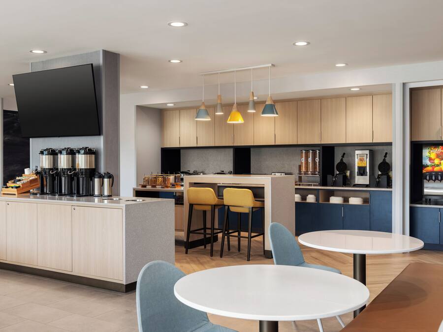 A modern kitchen with a central island, bar stools, and pendant lighting.