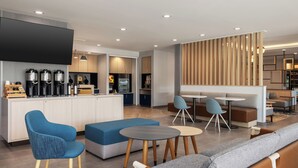 A modern kitchen with built-in appliances, a seating area with sofas and tables, and a wooden partition wall. - Towneplace Suites By Marriott Hickory (Hickory)