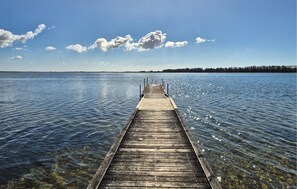 Une jetée en bois s’étendant sur une étendue d’eau calme, sous un ciel dégagé.