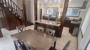 Cozinha moderna com bancadas de granito, eletrodomésticos de aço inoxidável e iluminação pendente.