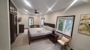 Quarto moderno com uma cama grande, uma escrivaninha, uma cadeira e um ventilador de teto.