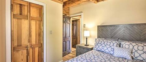 A bedroom with a bed, wooden wardrobe, and a nightstand with a lamp.