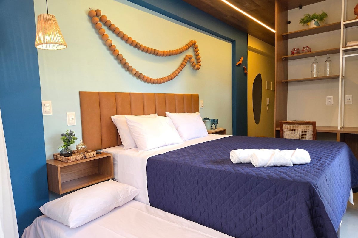 A hotel room with a bed, bedside tables, a wall-mounted lamp, and a decorative garland.