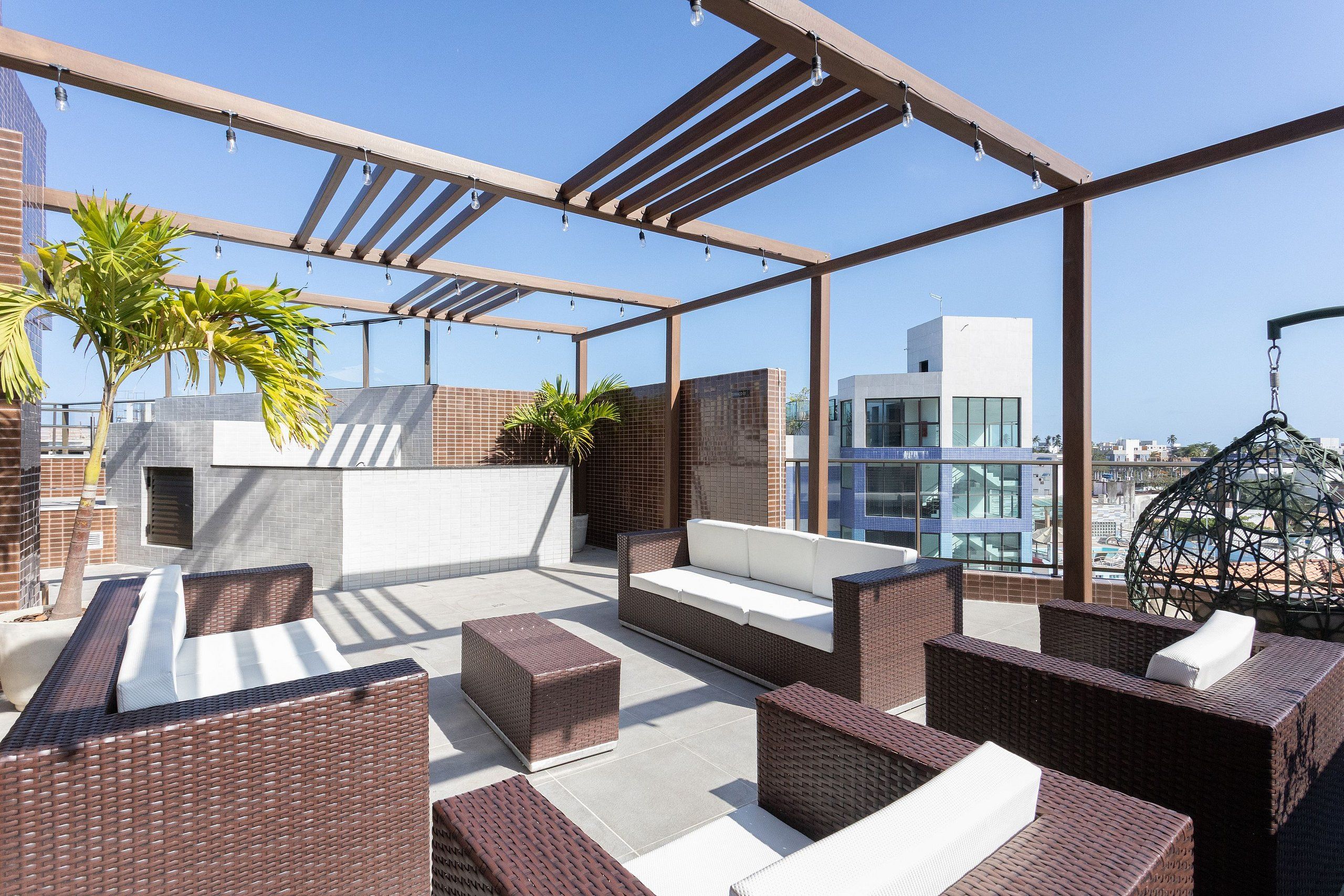 Eine Dachterrasse mit Korbmöbeln, einer Hängematte und Blick auf die Stadtlandschaft.