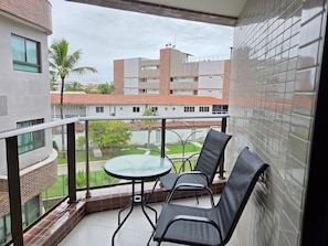 A balcony with a glass table and two chairs, overlooking a residential area with buildings and greenery. - SEASON Smart Flats by BLU stay (Ipojuca)