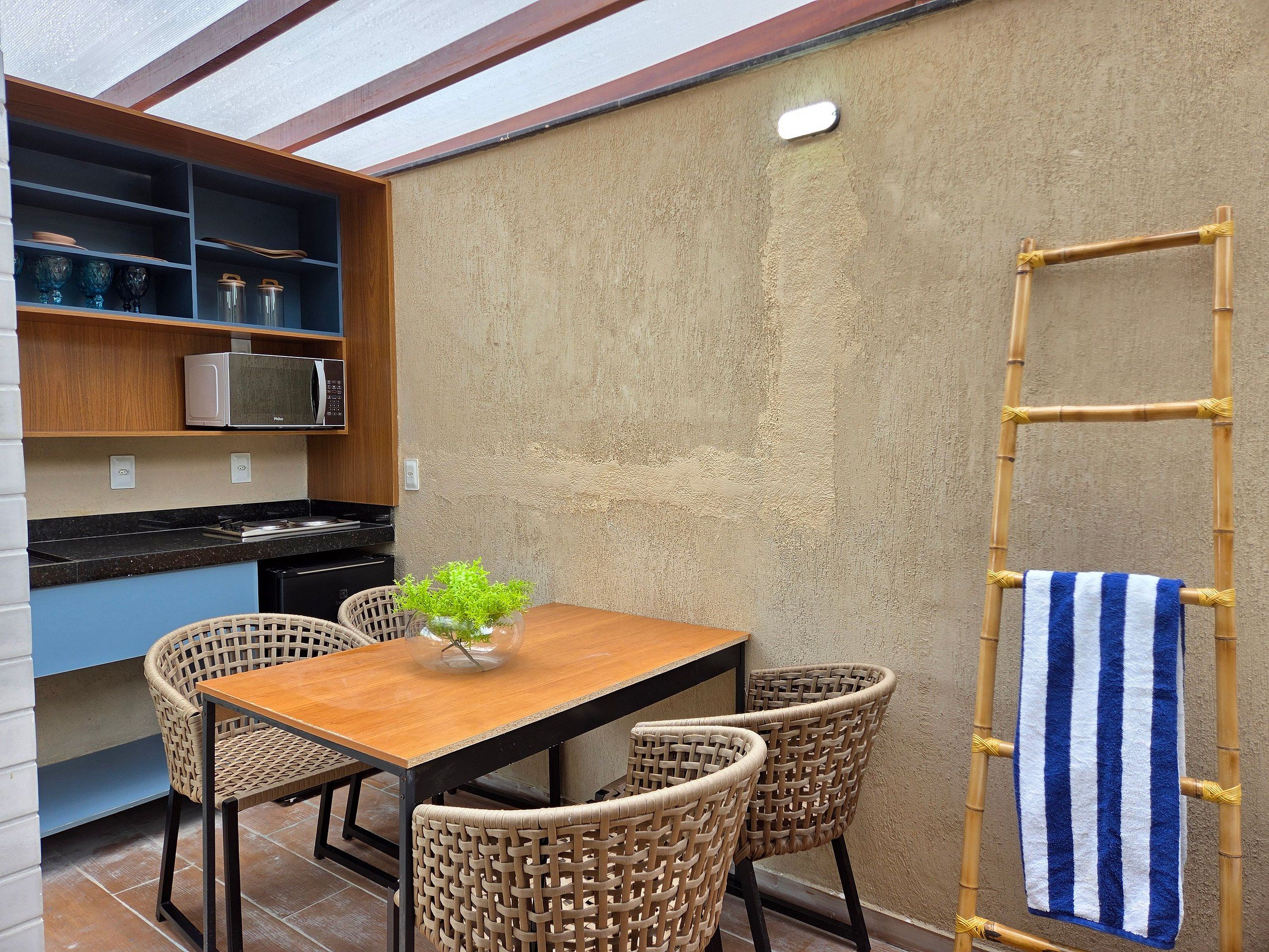 A kitchen with a microwave, cabinets, and a dining area with wicker chairs and a table.
