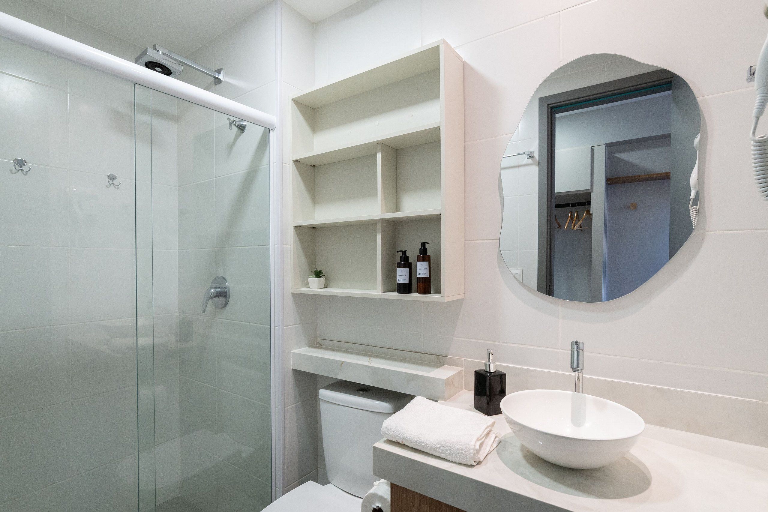 Un bagno moderno con cabina doccia in vetro, lavabo bianco e specchio con cornice tonda.