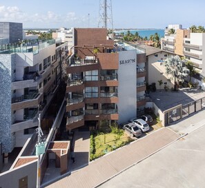 Un edificio a più piani con un cartello ben visibile 'SEASON SMART FLATS', una piscina sul tetto e vista sul mare.