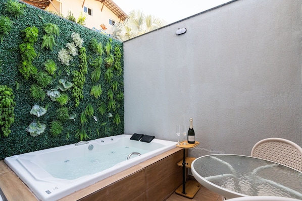 A spa area with a hot tub, a glass table, and a chair. - SEASON Smart Flats by BLU stay (Ipojuca)