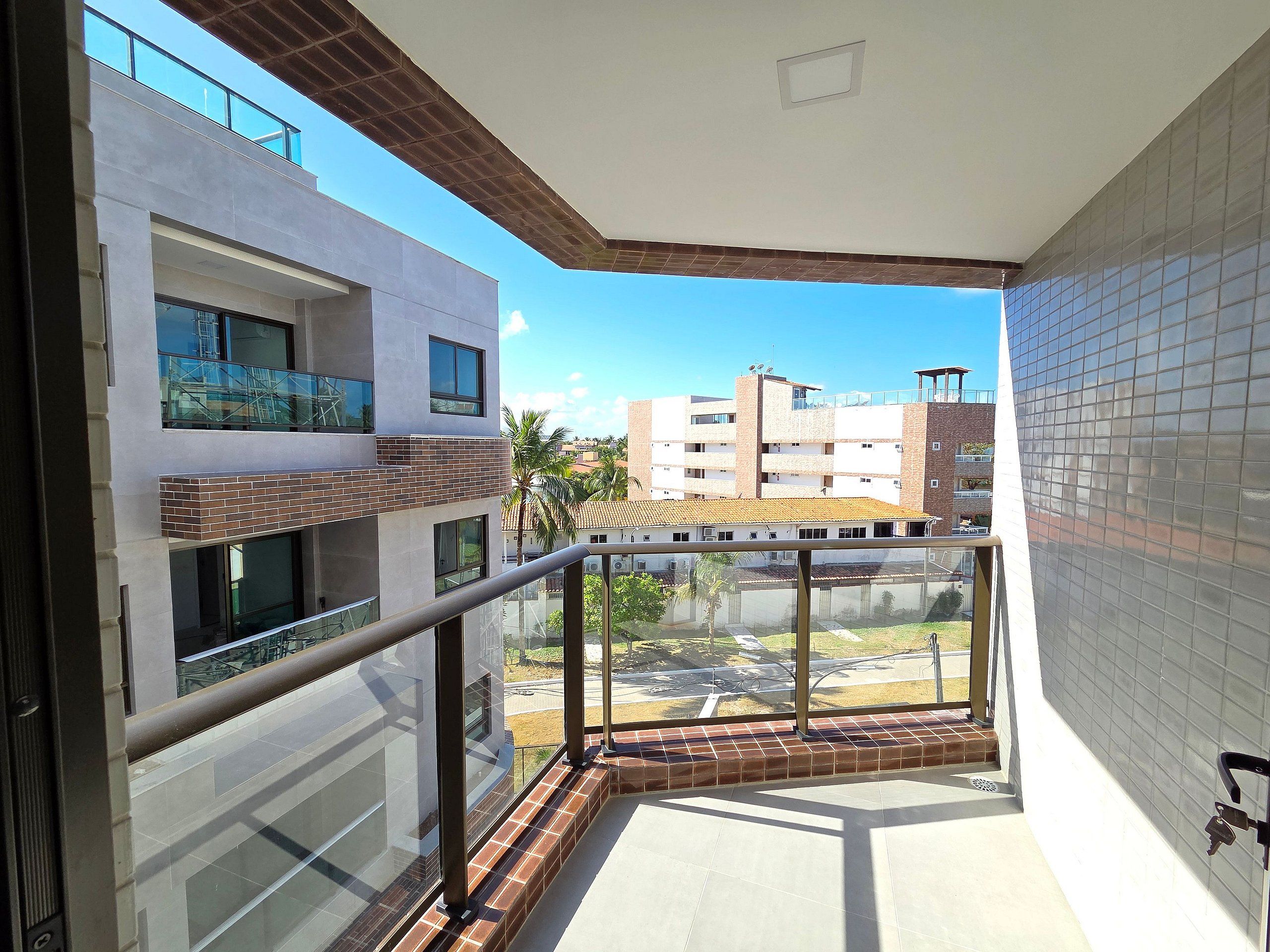 A balcony with a metal railing, a view of neighboring buildings, and a clear sky.