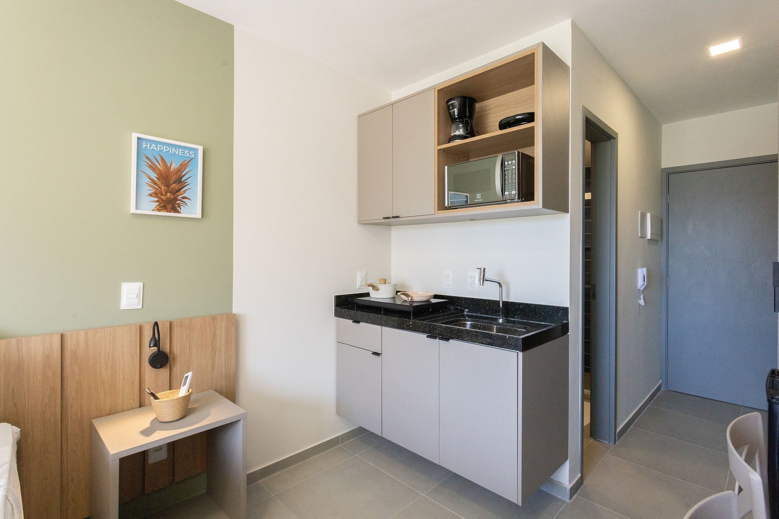 A compact kitchen with a microwave, coffee maker, and a small sink.