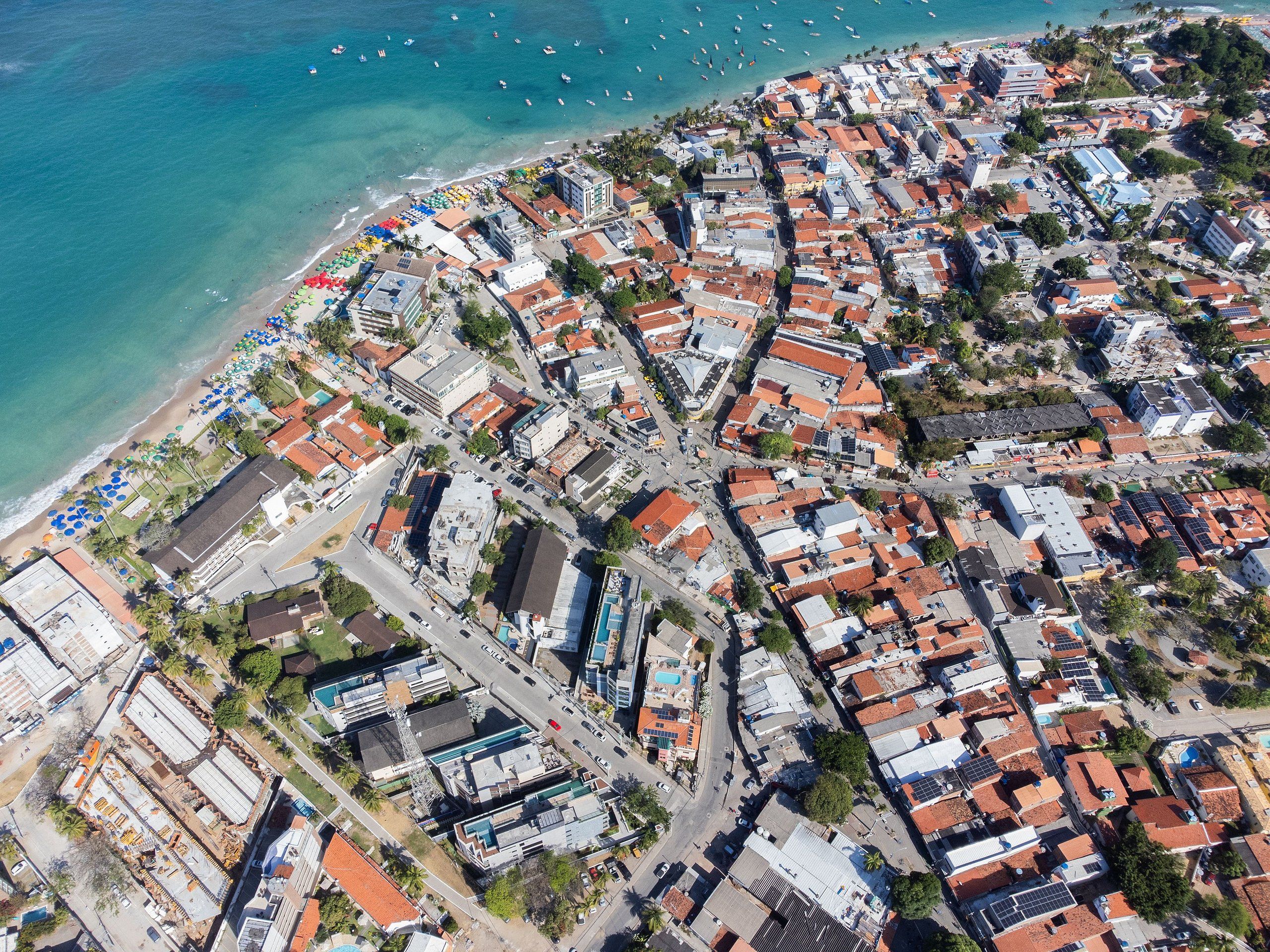 Une vue aérienne d’une ville côtière avec une plage, des bâtiments et des bateaux.