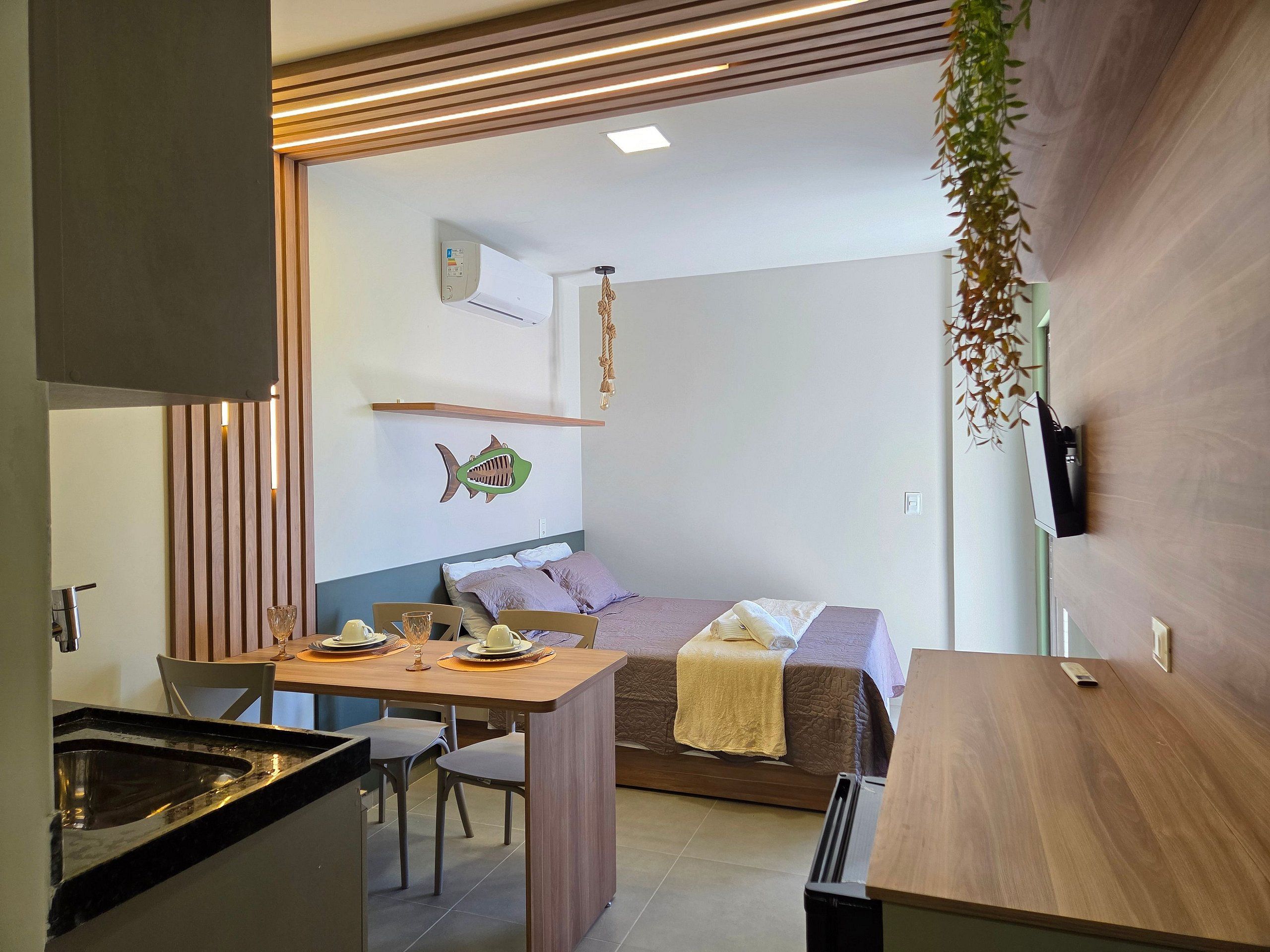 Un dormitorio moderno con cama, mesita de noche, televisor montado en la pared y un adhesivo decorativo de pez.
