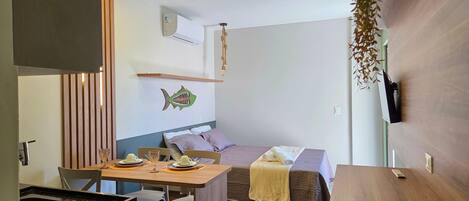 Un dormitorio moderno con cama, mesita de noche, televisor montado en la pared y un adhesivo decorativo de pez.