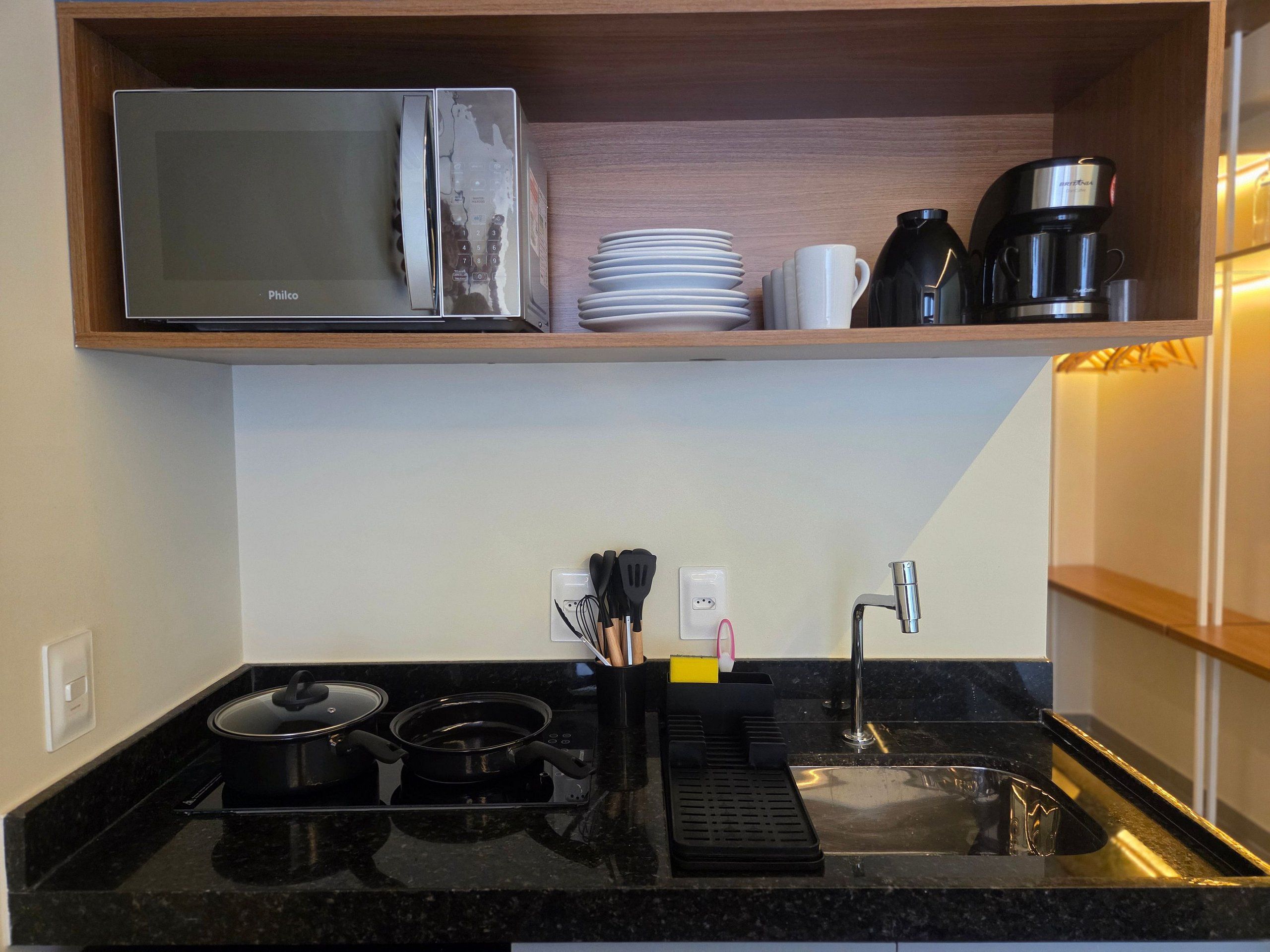A kitchen with a microwave, coffee maker, and a sink.