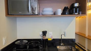 A kitchen with a microwave, coffee maker, and a sink.
