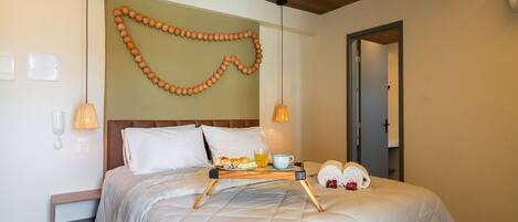 A hotel room with a bed, bedside lamps, a tray with breakfast items, and a wall decoration.