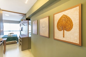 A hotel room with a bed, a desk, a chair, a radiator, and framed artwork on the wall. - SEASON Smart Flats by BLU stay (Ipojuca)