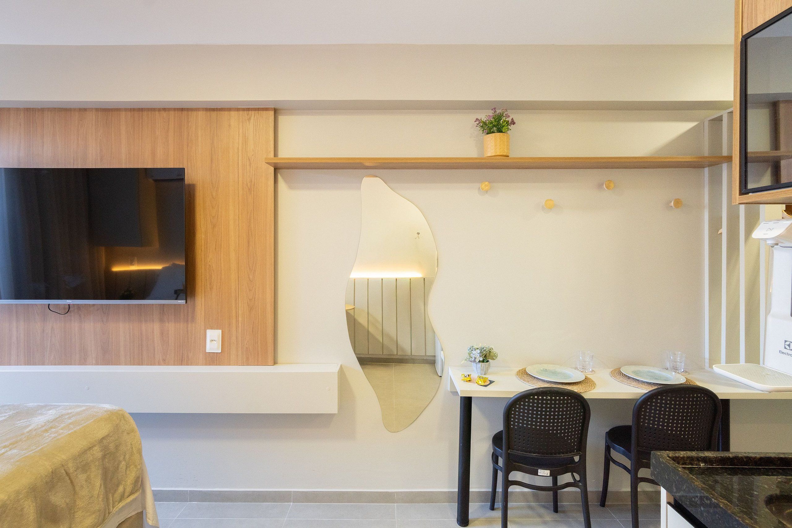 A modern dining area with a TV, wooden paneling, a mirror, and a table set for two.