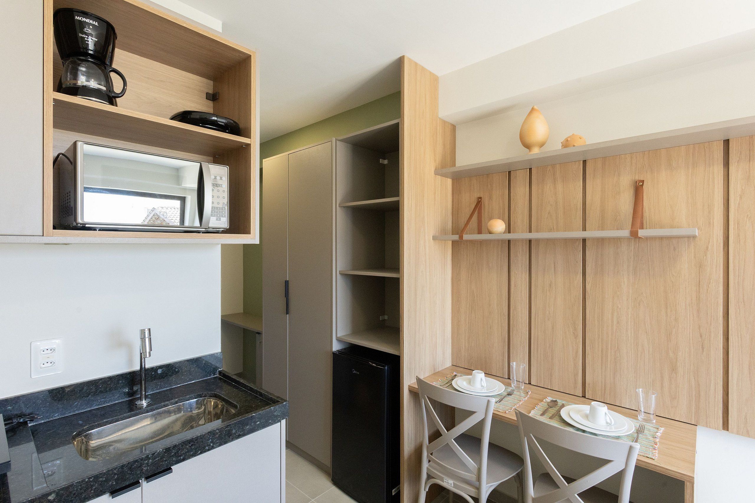 A compact kitchen with a built-in microwave, a coffee maker, and a small refrigerator.