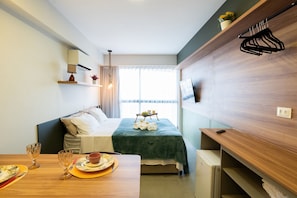 Una camera d'albergo con un letto, un comodino e una TV montata a parete.