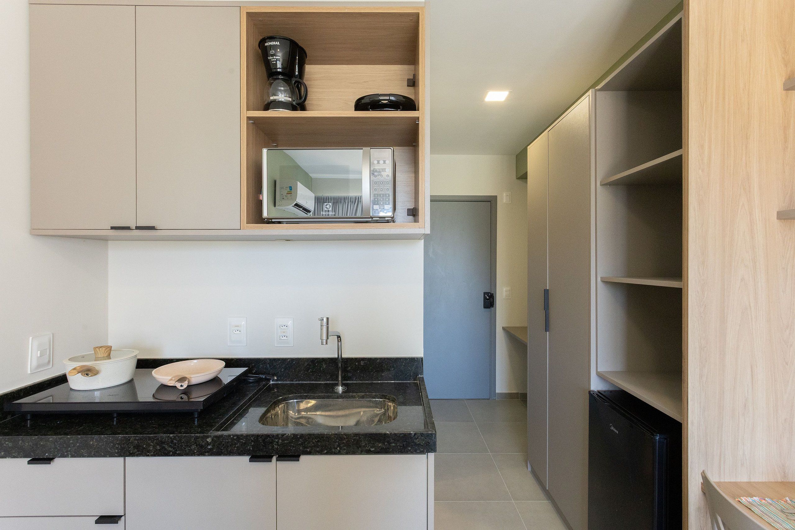 A modern kitchen with a black countertop, stainless steel sink, and wooden cabinets.