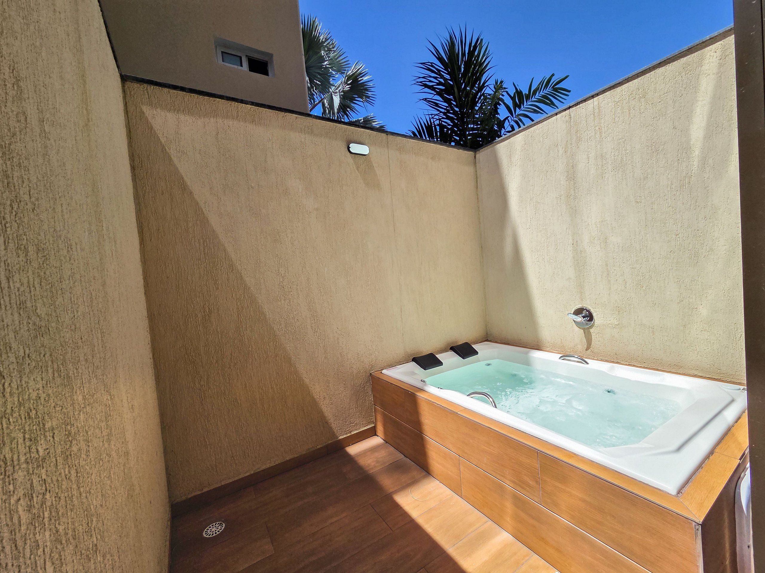 A spa area with a hot tub, wooden flooring, and a view of palm trees.