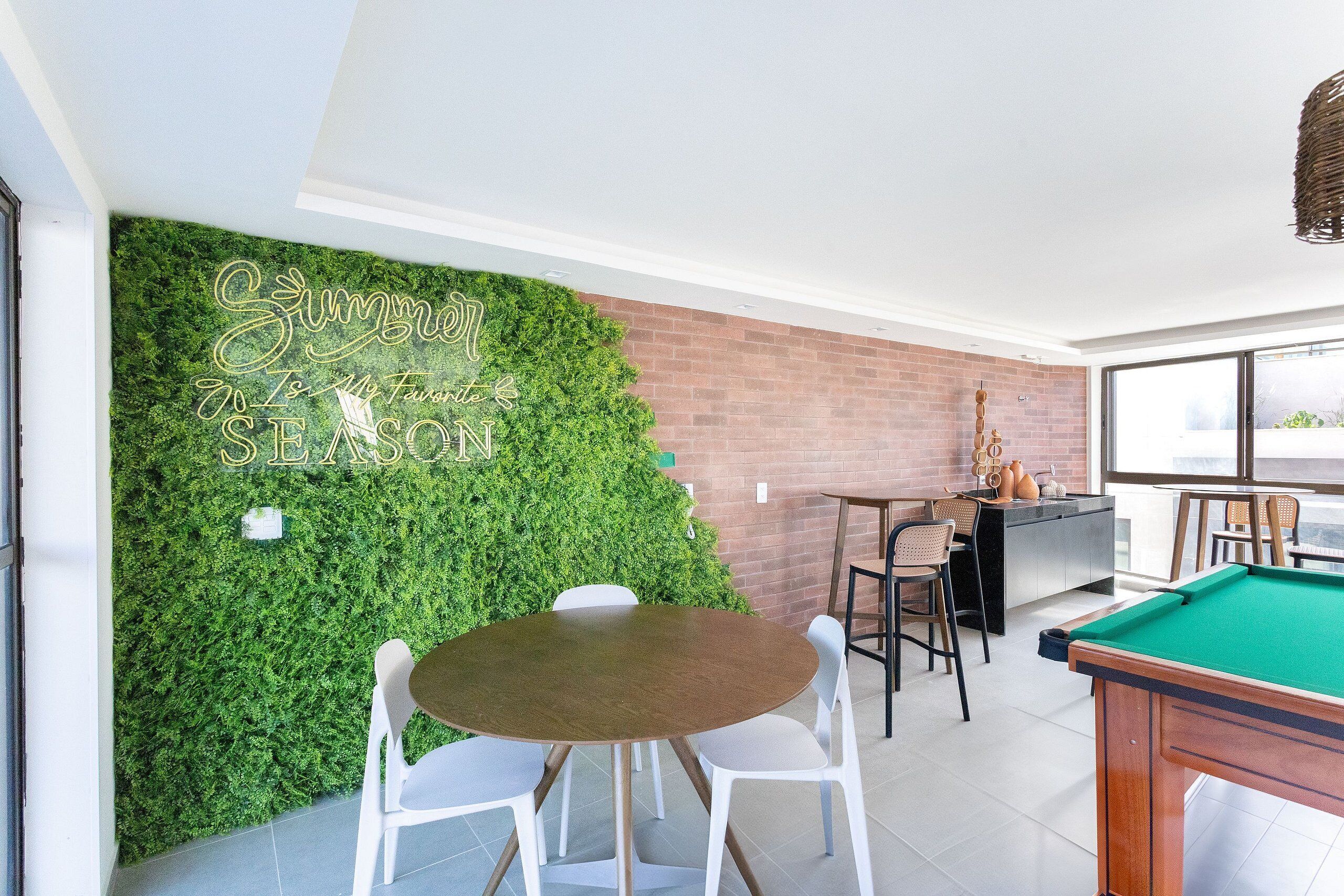 Una mesa de billar, una pared verde con un texto, y una pared de ladrillo.
