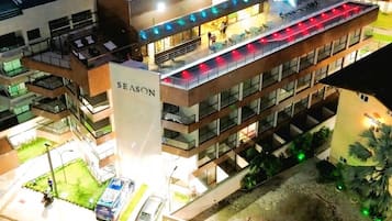 A multi-story building with a prominent 'SEASON' sign, outdoor seating, and a parking area.