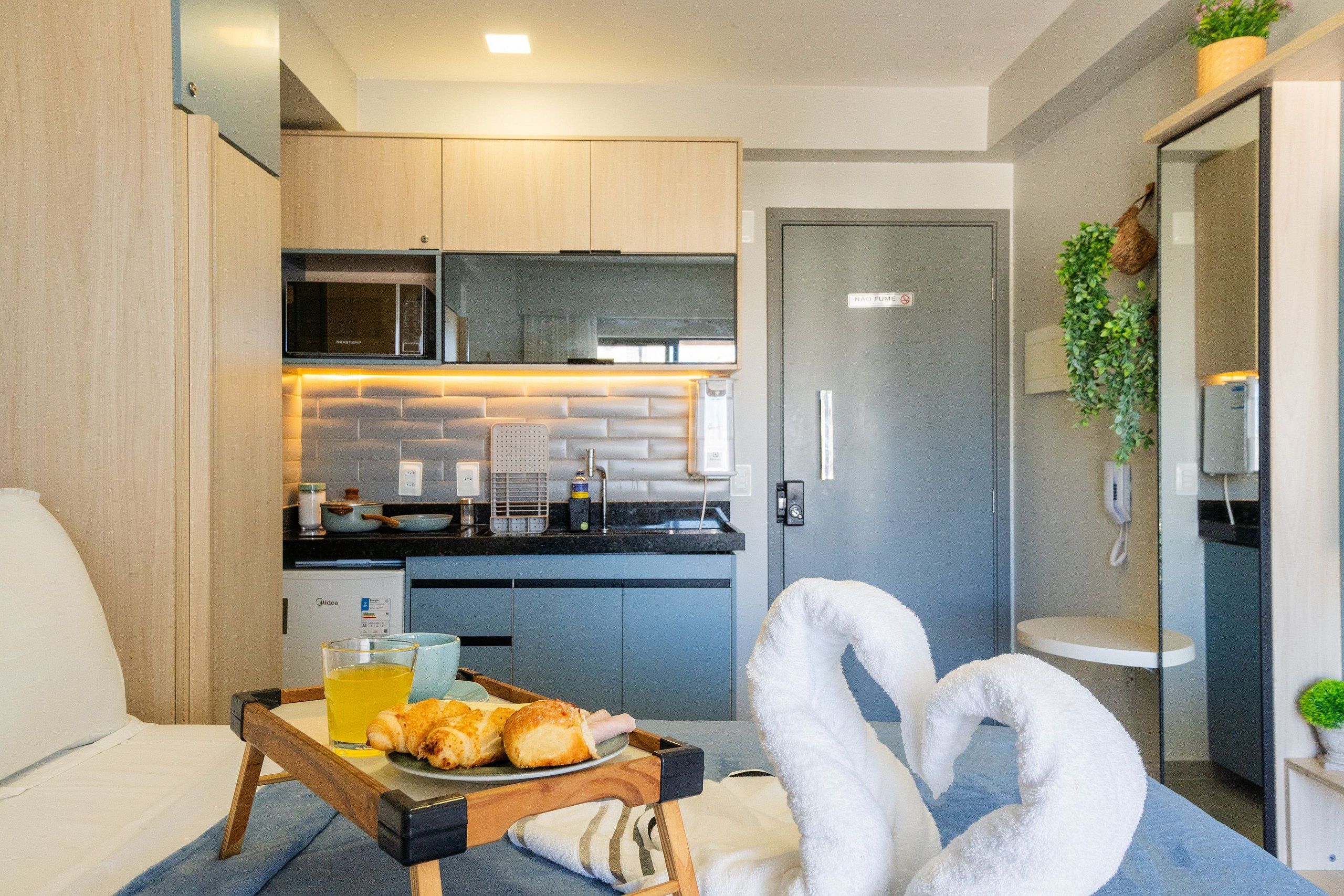 A compact kitchen with modern appliances, a dining area with a tray of food, and a cozy seating arrangement.
