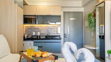 A compact kitchen with modern appliances, a dining area with a tray of food, and a cozy seating arrangement.