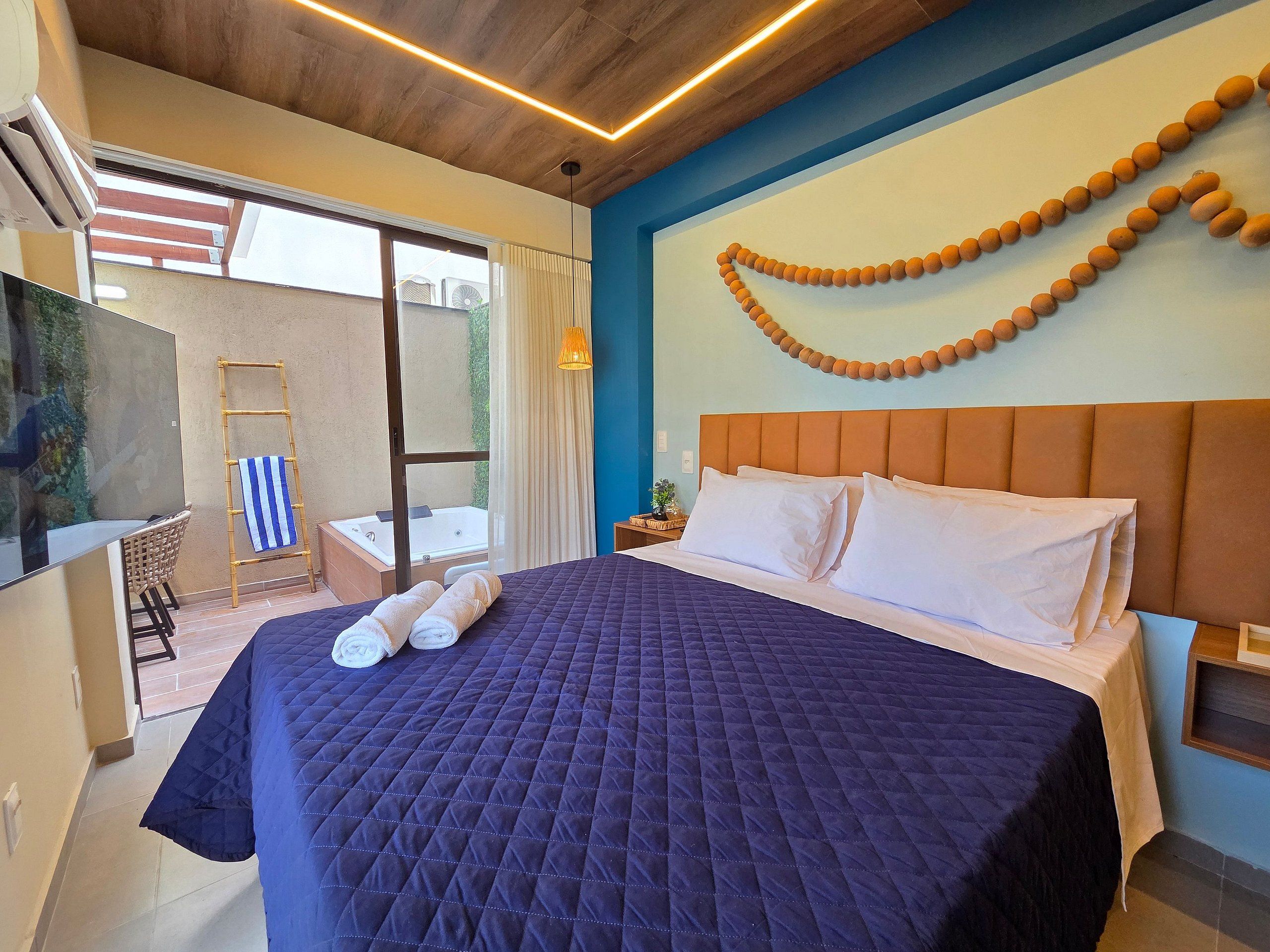 Camera da letto con un ampio letto, vista sull'esterno, soffitto in legno e una decorazione a parete.