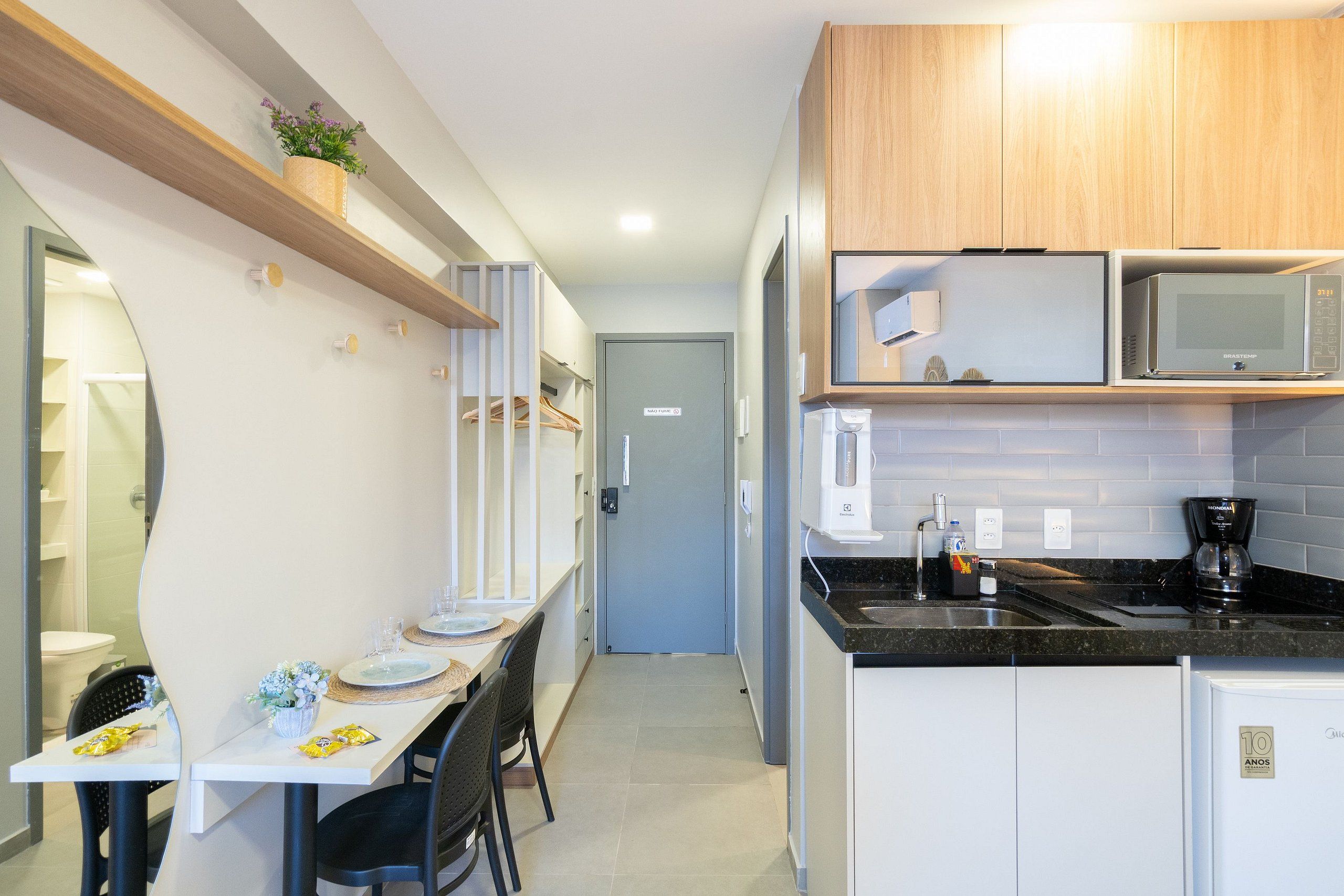 Una cocina compacta con microondas, cafetera y un refrigerador pequeño.